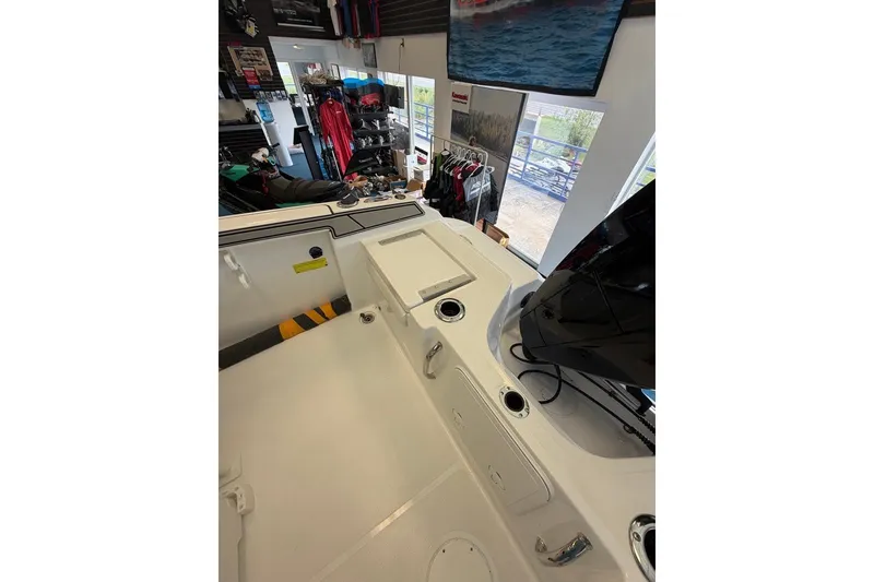 Slide: The Image of 2027 Wellcraft 202 Fisherman boat interior, showcasing deck and storage features in a showroom. - 13