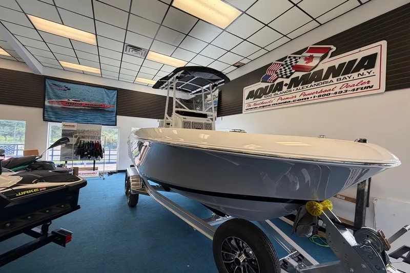 Slide: The Image of 2027 Wellcraft 202 Fisherman boat displayed indoors at Aqua-Mania dealership. - 4