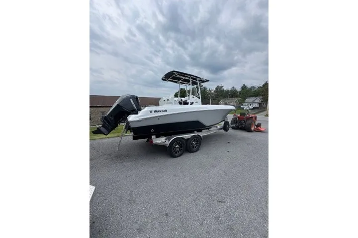 Slide: The Image of 2027 Wellcraft 202 Fisherman boat on trailer, parked outdoors under cloudy sky. - 2