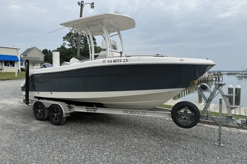 The Image of 2022 Robalo R222 Center Console boat on trailer near waterfront dock. - 1