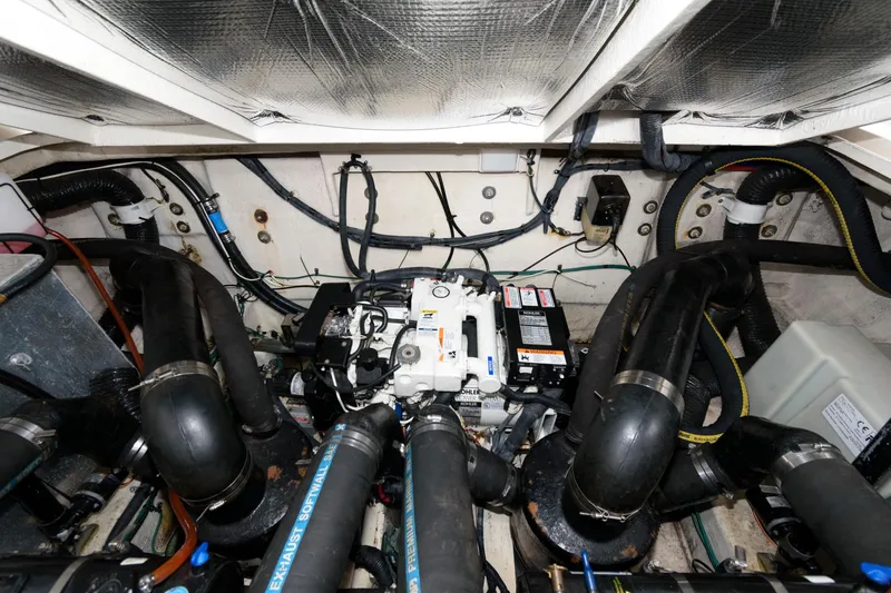 Slide: The Image of The engine room of a 2006 Sea Ray Sundancer 320 shows complex piping and wiring. - 23