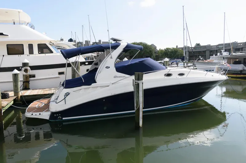 Slide: The Image of A 2006 Sea Ray Sundancer 320 docked in a marina, featuring a sleek design and blue hull. - 1
