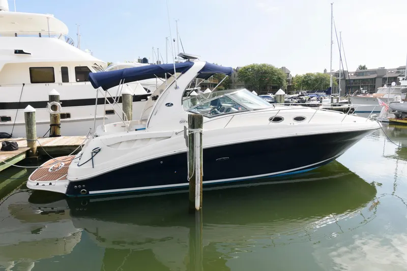 The Image of A 2006 Sea Ray Sundancer 320 docked in the water, featuring a blue canopy. - 0