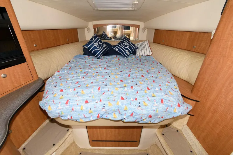 Slide: The Image of Cabin of the 2006 Sea Ray Sundancer 320 with a cozy bed and nautical-themed bedding. - 18