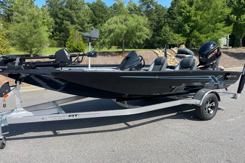 The Image of 2027 Xpress H18 boat on trailer, parked outdoors with trees in background. - 0