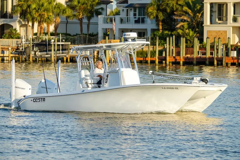 Slide: The Image of 2020 Costa Custom Boats 264HC cruising on a sunny waterfront with palm trees. - 14