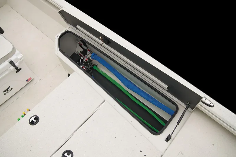 Slide: The Image of The image shows a storage compartment on a 2024 Ranger RB210 boat with fishing rods. - 36