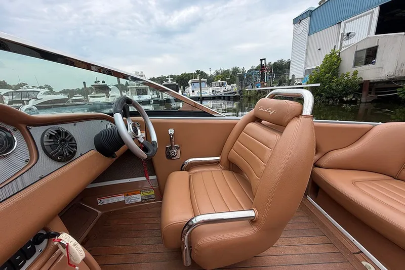 Slide: The Image of 2011 Chris-Craft Silver Bullet 20 boat interior with tan leather seats and wooden flooring. - 14