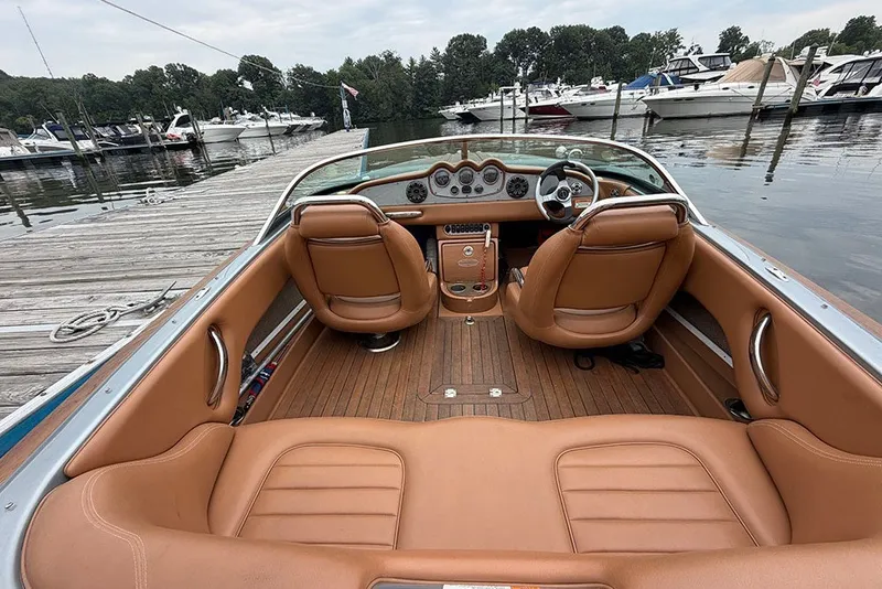 Slide: The Image of 2011 Chris-Craft Silver Bullet 20 boat interior with tan leather seats at a marina. - 10