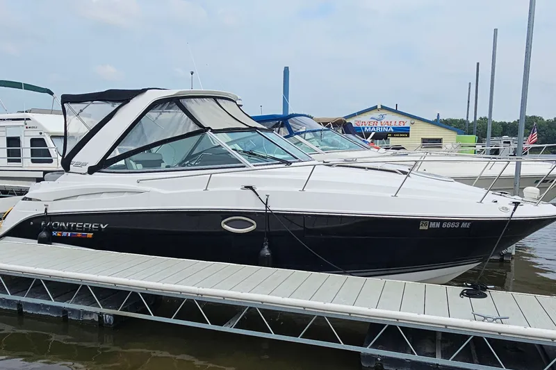 Slide: The Image of 2021 Monterey 295 Sport Yacht docked at marina, sleek design, black and white exterior. - 2
