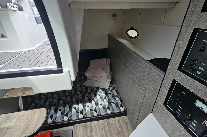 Slide: The Image of 2021 Monterey 295 Sport Yacht interior cabin with bed and control panels. - 17
