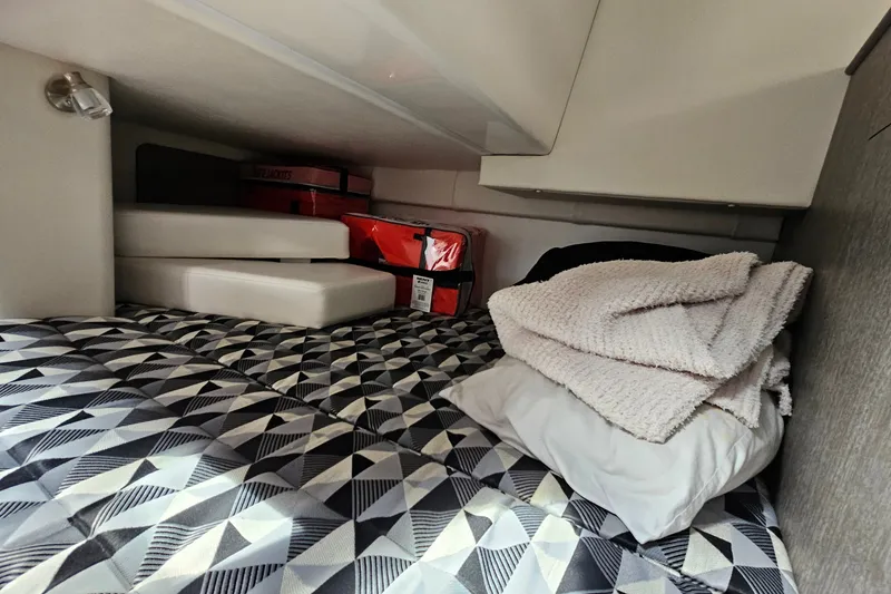 Slide: The Image of Cozy cabin interior of 2021 Monterey 295 Sport Yacht with geometric bedding and storage. - 18