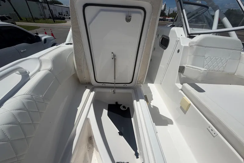 Slide: The Image of 2023 Edgewater 248CX Crossover boat interior with open storage compartment and white seating. - 70