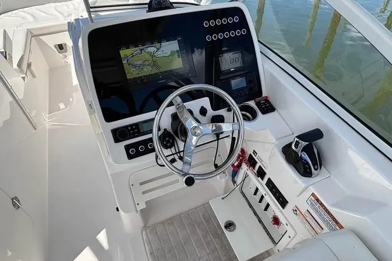 Slide: The Image of 2023 Edgewater 248CX Crossover boat cockpit with steering wheel and navigation controls. - 20
