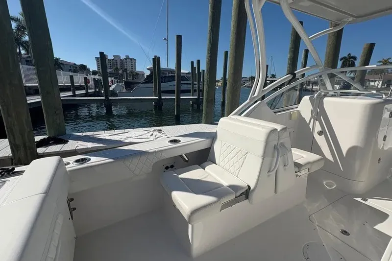 Slide: The Image of 2023 Edgewater 248CX Crossover boat interior at marina, featuring white seating and clear skies. - 29