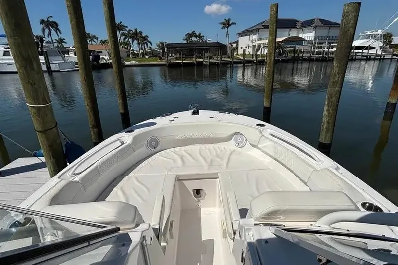 Slide: The Image of 2023 Edgewater 248CX Crossover boat docked in a serene marina setting. - 19