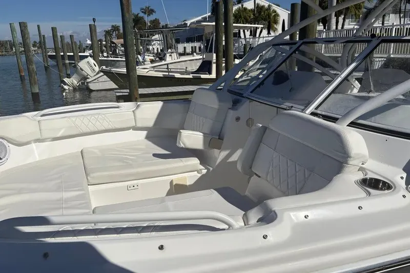 Slide: The Image of 2023 Edgewater 248CX Crossover boat interior with white seating at a marina. - 37
