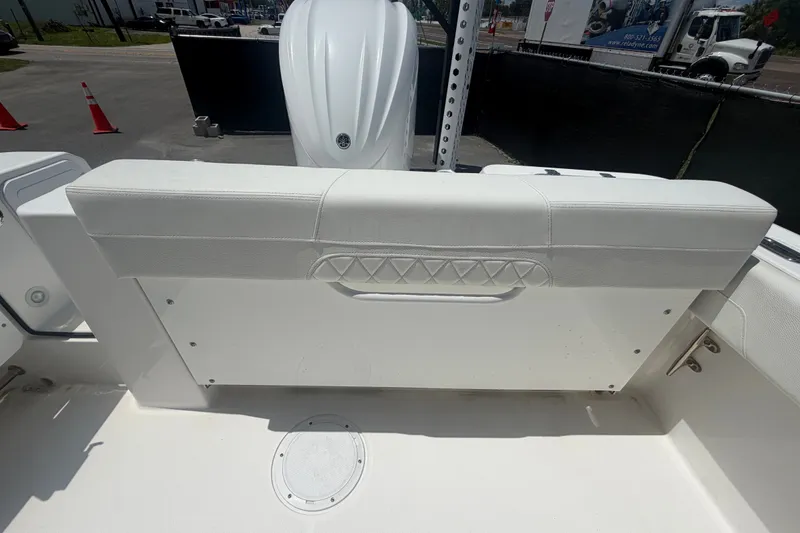 Slide: The Image of 2023 Edgewater 248CX Crossover boat interior with white seating and engine view. - 82