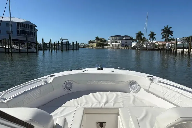 Slide: The Image of 2023 Edgewater 248CX Crossover boat in a scenic marina with palm trees. - 34