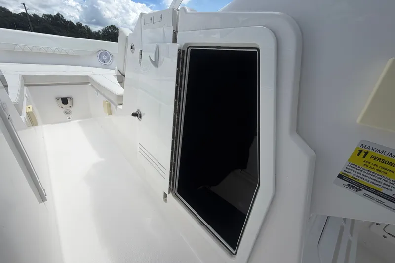 Slide: The Image of 2023 Edgewater 248CX Crossover boat interior with open storage compartment and seating area. - 56