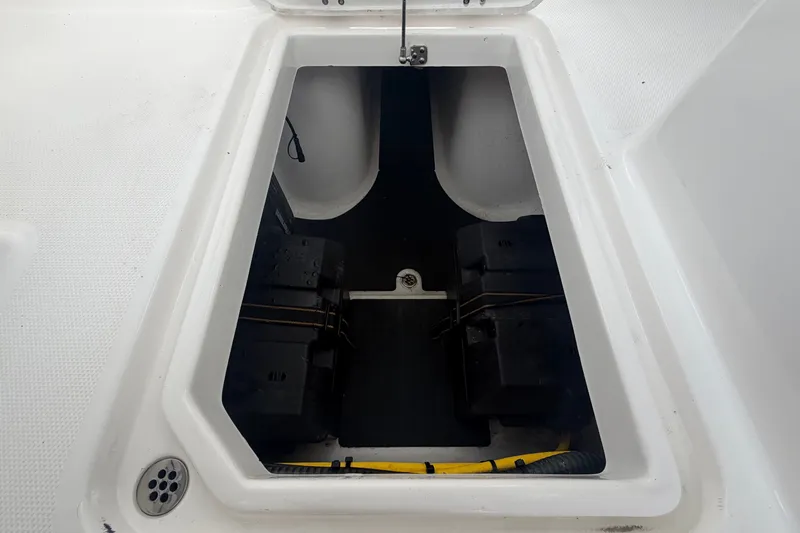 Slide: The Image of A storage compartment in the Edgewater 248CX Crossover boat with batteries and cables. - 24