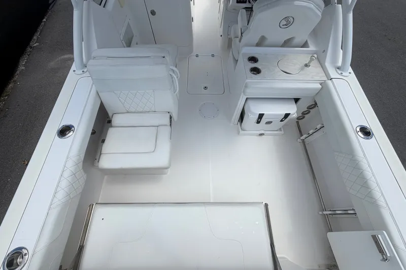 Slide: The Image of 2023 Edgewater 248CX Crossover boat interior with white seating and storage compartments. - 16