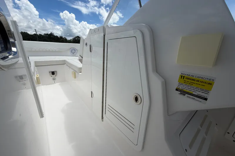 Slide: The Image of 2023 Edgewater 248CX Crossover boat interior with storage compartment and capacity label. - 55