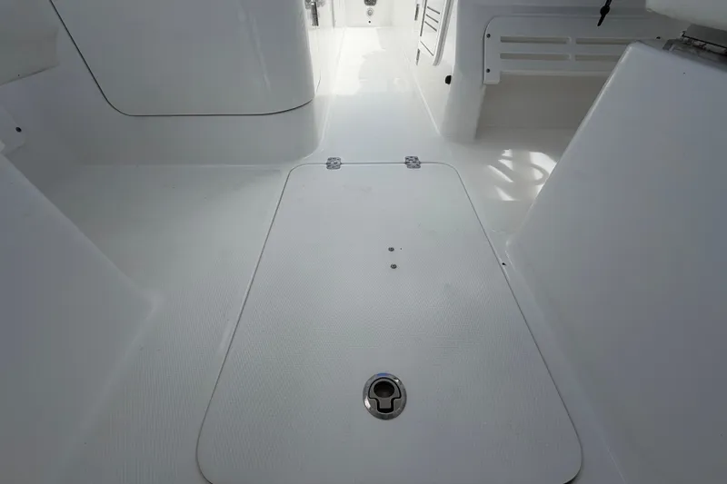Slide: The Image of 2023 Edgewater 248CX Crossover boat interior, featuring sleek white flooring and storage compartment. - 23