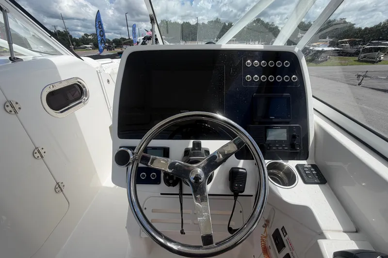 Slide: The Image of 2023 Edgewater 248CX Crossover boat dashboard with steering wheel and control panel. - 38