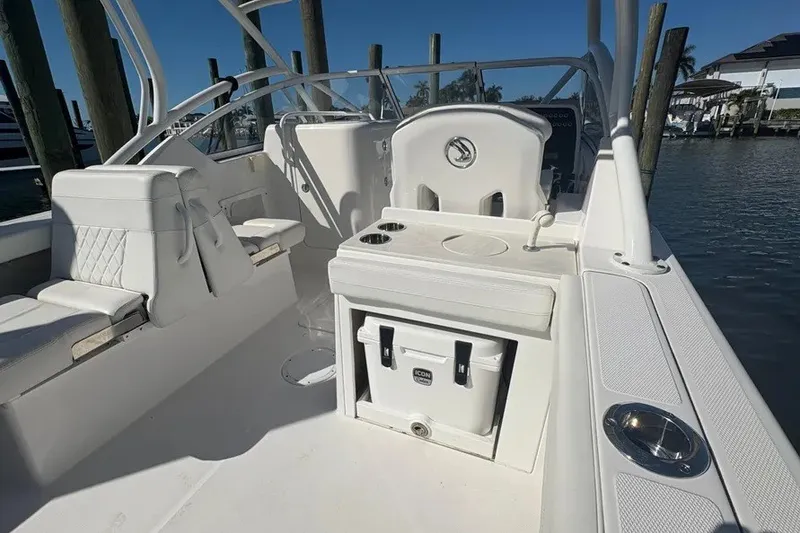 Slide: The Image of 2023 Edgewater 248CX Crossover boat interior with seating and storage, docked by the water. - 28