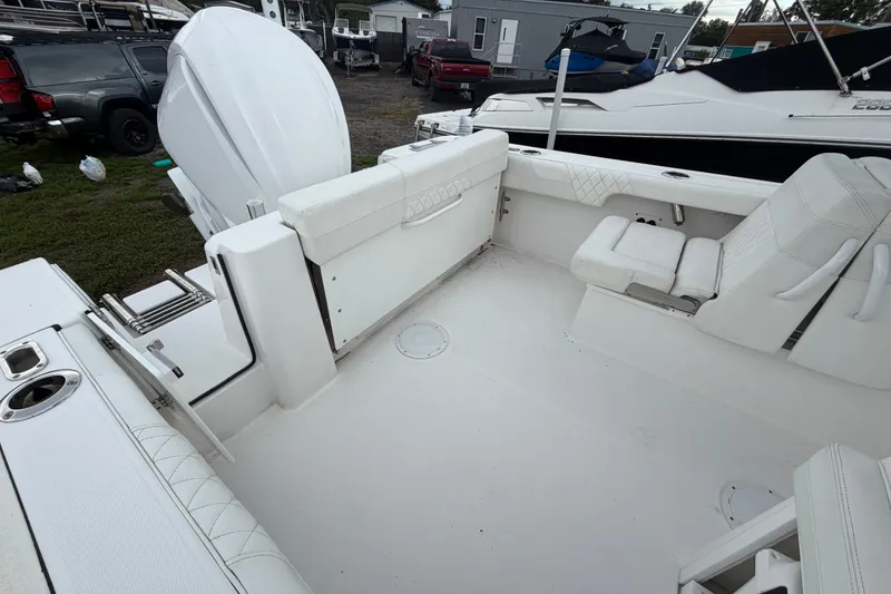 Slide: The Image of 2023 Edgewater 248CX Crossover boat interior with white seating and motor. - 3