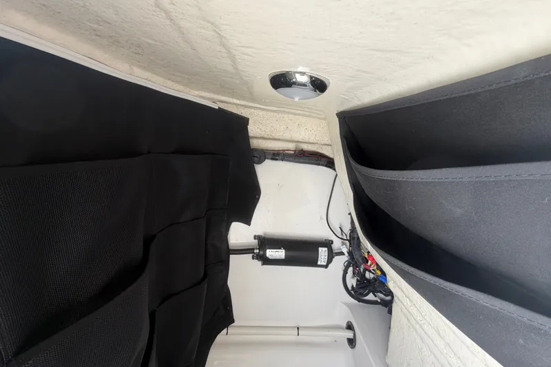 Slide: The Image of Interior view of 2023 Edgewater 248CX Crossover boat storage compartment with black fabric lining. - 57