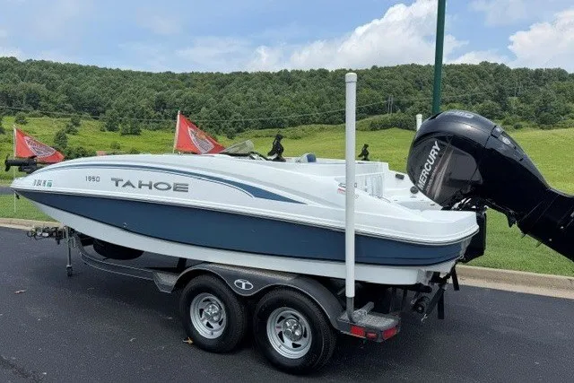 Slide: The Image of Tahoe 1950 boat from 2017 on trailer, with Mercury outboard motor, parked outdoors. - 3
