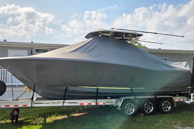 Slide: The Image of 2022 Tidewater 282 CC Adventure boat covered on trailer, parked outdoors. - 23