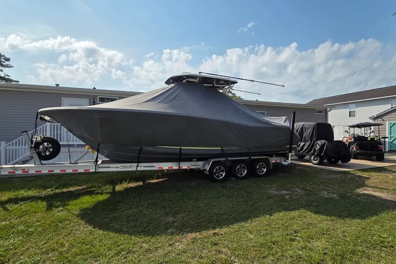Slide: The Image of Covered 2022 Tidewater 282 CC Adventure boat on trailer, parked beside a house. - 24
