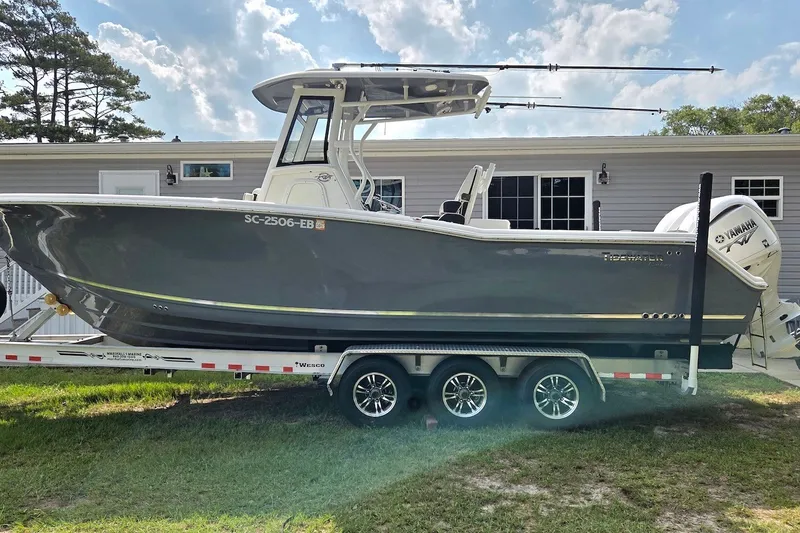 The Image of 2022 Tidewater 282 CC Adventure boat on trailer, parked near a house. - 0