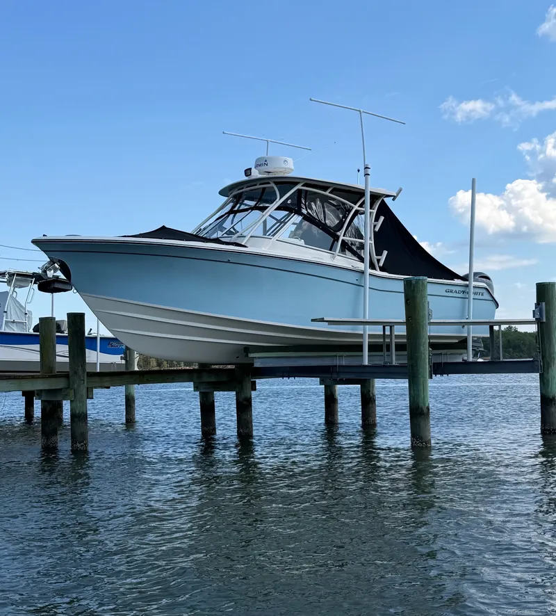 Slide: The Image of A 2022 Grady-White Freedom 275 boat is on a lift above the water. It features a blue hull design. - 1