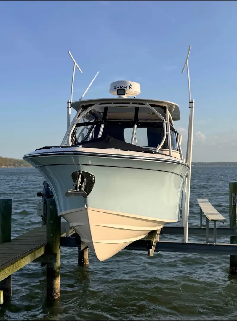 Slide: The Image of A 2022 Grady-White Freedom 275 boat on a lift by the water. - 2