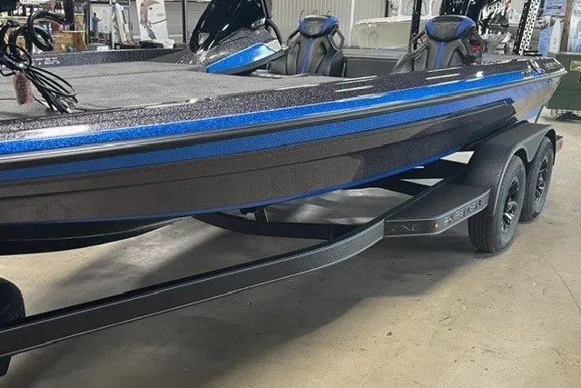 The Image of 2027 Skleeter ZXE20 boat with sleek design and dual axle trailer in a showroom. - 0