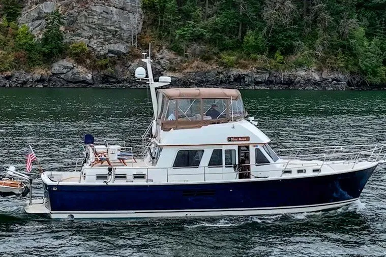 Slide: The Image of 2000 Sabreline 47 yacht cruising on a scenic waterway with lush greenery. - 16