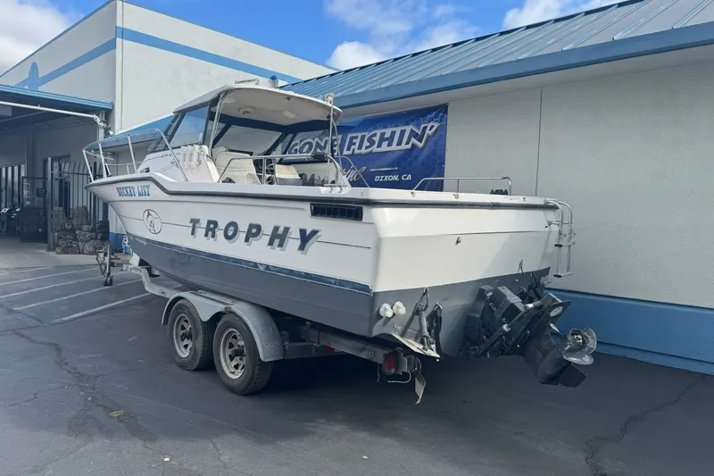 Slide: The Image of 1995 Bayliner 2302 Trophy Walkaround boat on trailer, parked outside a building. - 5