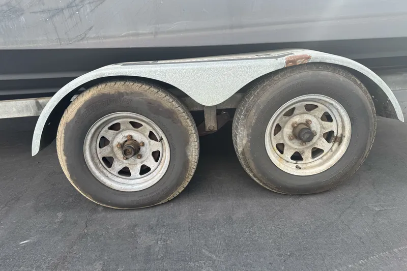Slide: The Image of Trailer wheels of a 1995 Bayliner 2302 Trophy Walkaround boat on pavement. - 4