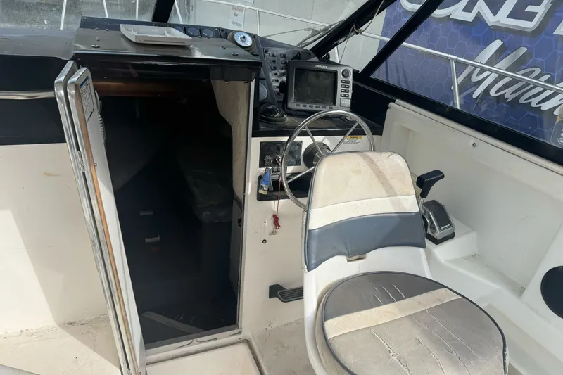 Slide: The Image of 1995 Bayliner 2302 Trophy Walkaround boat cockpit with steering wheel and navigation equipment. - 11