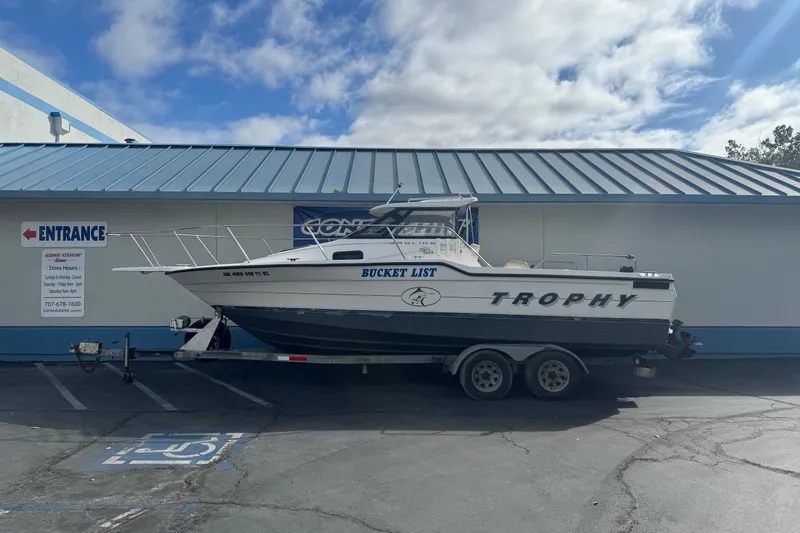 The Image of 1995 Bayliner 2302 Trophy Walkaround boat on trailer, parked outside a building. - 0