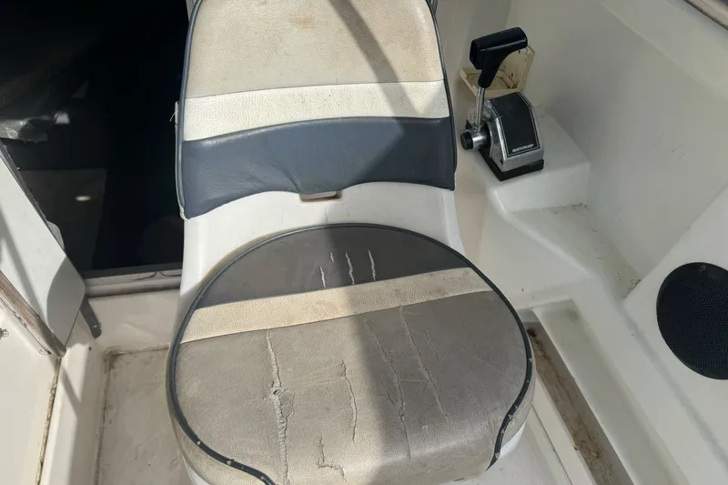 Slide: The Image of 1995 Bayliner 2302 Trophy Walkaround boat seat with visible wear and control lever. - 13