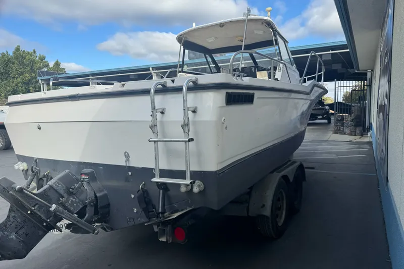 Slide: The Image of 1995 Bayliner 2302 Trophy Walkaround boat on trailer, parked outdoors under cloudy sky. - 7