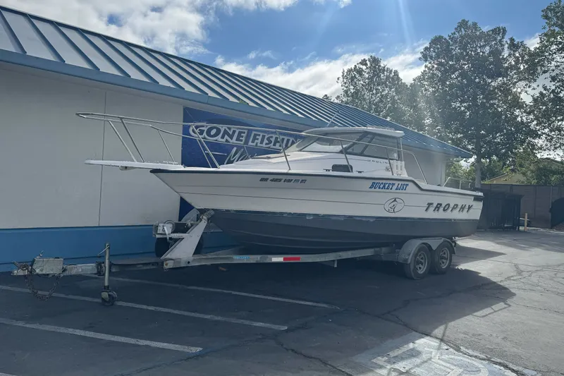 Slide: The Image of 1995 Bayliner 2302 Trophy Walkaround boat on trailer, parked outside a building. - 1