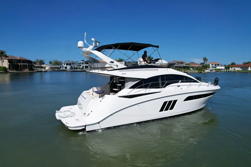 Slide: The Image of 2014 Sea Ray 510 Fly yacht cruising on a calm, sunny waterfront. - 1