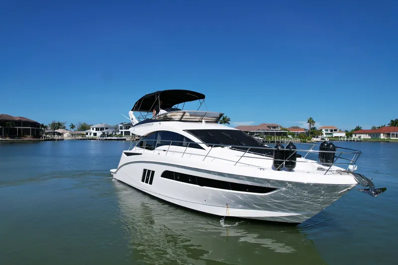 Slide: The Image of 2014 Sea Ray 510 Fly yacht cruising on a sunny day in a residential waterfront area. - 57