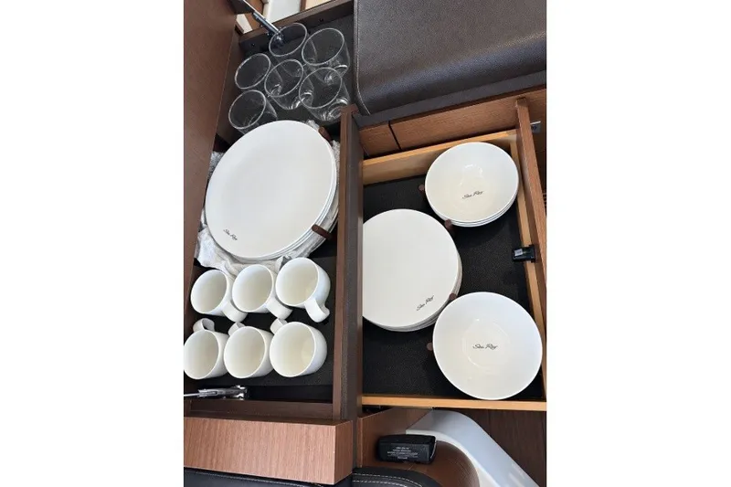 Slide: The Image of Ceramic dishware set in a Sea Ray 510 Fly yacht's drawer, featuring plates, bowls, and mugs. - 13